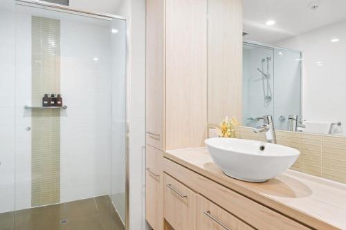Un baño con lavabo blanco y ducha. en 2BR CBD Apt Swimming Pool Sauna SPA CBD, en Adelaida