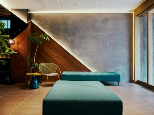 a lobby with two blue ottomans and a wall at R Hotel Kansai Airport in Izumi-Sano