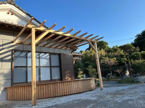 a wooden pergola on the side of a house at ゲストハウス奥屋敷城内 in Kinko