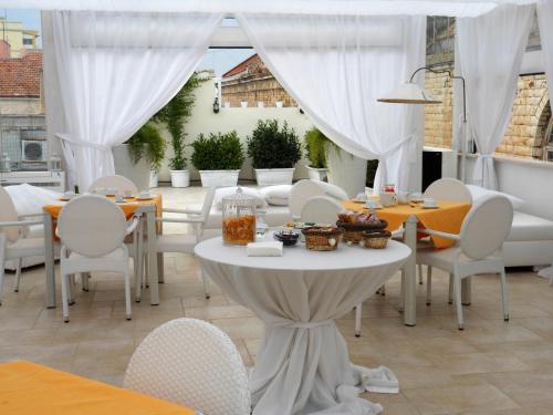 a patio with white tables and chairs and a table with food on it at Palazzo Antica Via Appia in Bitonto
