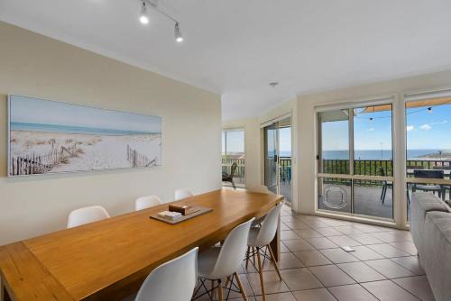 a dining room with a table and chairs and the ocean at 48 Rumbelow St - BYO Linen - Sea Views - Family Friendly in Encounter Bay