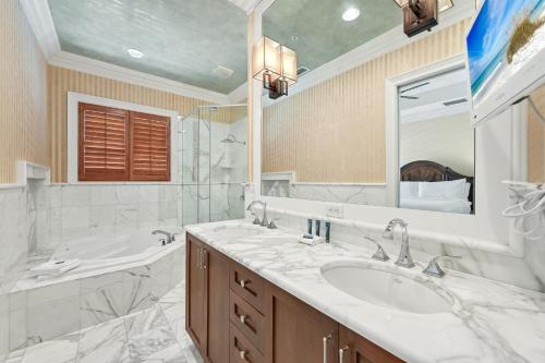 a bathroom with a sink and a tub and a mirror at Le Jardin 154 in Destin