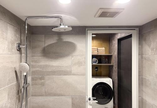 uma casa de banho com uma máquina de lavar roupa e um chuveiro. em Nexus Gotanda em Tóquio