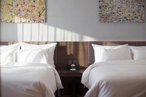 two beds in a hotel room with white sheets at Dignity Hotel in Yangyang