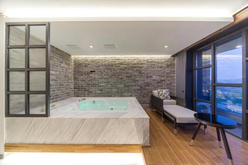 a large bathroom with a tub with a chair and a table at Dignity Hotel in Yangyang