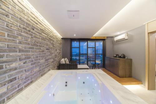 a hot tub in a room with a brick wall at Dignity Hotel in Yangyang