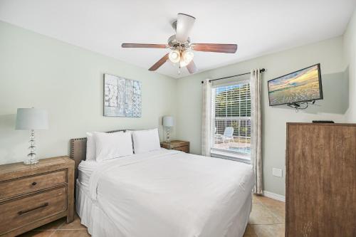 1 dormitorio con cama blanca y ventilador de techo en Salty Seas 405 Sandy Cay en Destin