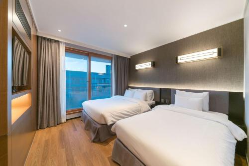 a hotel room with two beds and a large window at Dignity Hotel in Yangyang