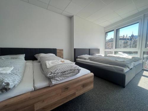two beds in a room with a large window at Simplex Apartments Am Schwabentorring in Freiburg im Breisgau