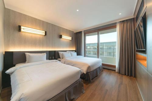 a hotel room with two beds and a window at Dignity Hotel in Yangyang