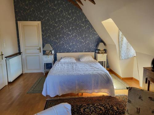 a bedroom with a bed with a blue wall at Charmante maison du XVe avec piscine, jardin et terrasse en lisière de la forêt de Tronçais - FR-1-489-217 in Le Brethon