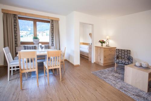 a dining room with a table and chairs and a bedroom at Alpenherz Ferienwohnungen in Pertisau