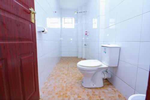baño con aseo blanco y puerta roja en Luxurious furnished home thika road en Nairobi