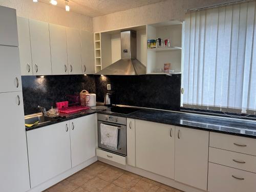 eine Küche mit weißen Schränken und einer schwarzen Arbeitsplatte in der Unterkunft karakolev 3 in Obrochishte