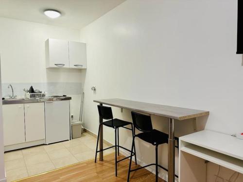 une cuisine avec un comptoir et deux tabourets de bar dans l'établissement Superbe studio proche du Casino/Stade de France, à Soisy-sous-Montmorency