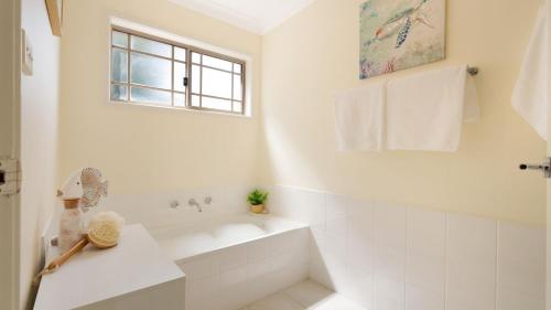 a white bathroom with a tub and a sink at Bombo Blue in Kiama