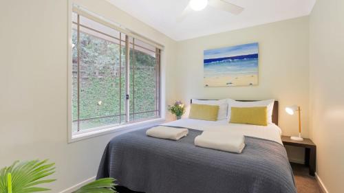 a bedroom with a large bed with two windows at Bombo Blue in Kiama