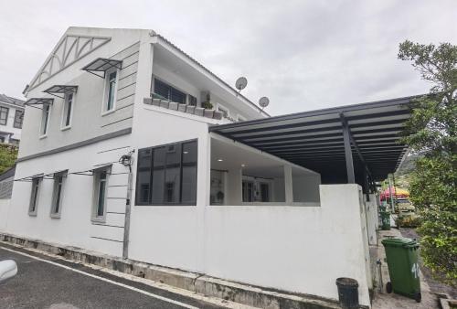 a white house with a white wall at Cosy 2-Storey Holiday Home Vines 2 @Pasar Malam -1 in Brinchang