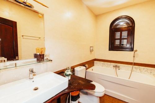 une salle de bains avec lavabo, baignoire et toilettes dans l'établissement Villa Trung Nghĩa 38, à Khu Chi Lăng
