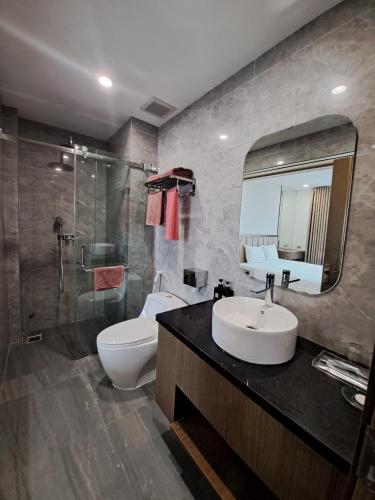 a bathroom with a sink and a toilet and a mirror at Glory Hotel Apartment Hải Phòng in Hai Phong