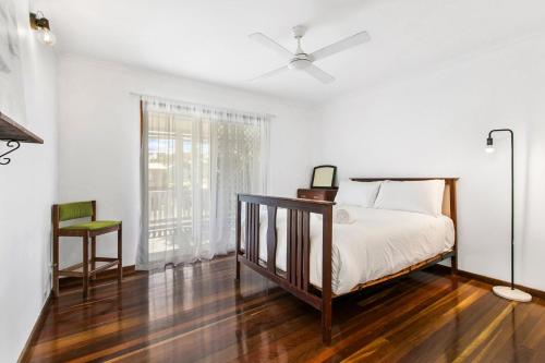 a white bedroom with a bed and a window at Unwind on Prince in Urangan