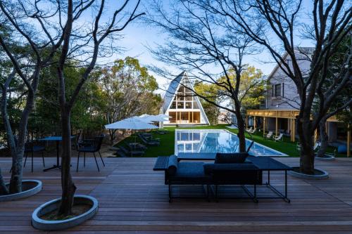 eine Terrasse mit Pool und Bäumen und ein Haus in der Unterkunft クラフトホテル瀬戸内 in Higashikagawa