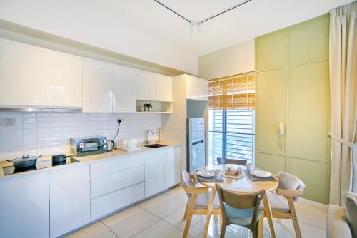 a kitchen with white cabinets and a table and chairs at Continew Residence TRX KL in Kuala Lumpur
