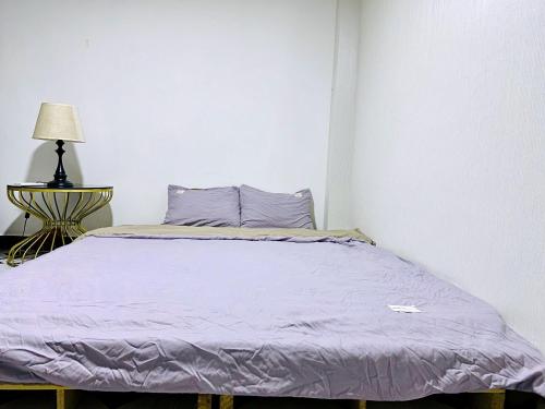 um quarto com uma cama com lençóis roxos e um candeeiro em SÀI GÒN INN ĐỀ THÁM em Ho Chi Minh