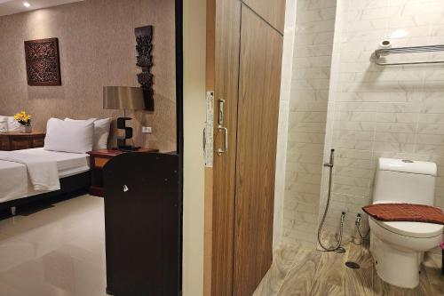 a bathroom with a toilet and a room with a bed at Kim Hotel At Bangplong in Ban Bang Prong