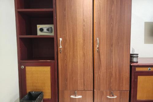 a wooden cabinet with a microwave in a room at Kim Hotel At Bangplong in Ban Bang Prong