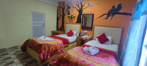 a hotel room with two beds and birds on the wall at Hong Qi Hotel in Chitwan