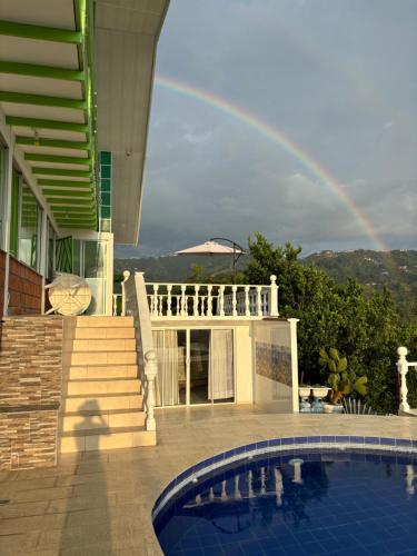 a rainbow in the sky over a house with a pool at Villa NiNa in Manizales