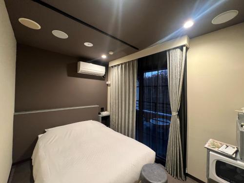 仙台市にあるHotel 螢月ｰhozukiｰ Adult Onlyのベッドと窓が備わる小さな客室です。