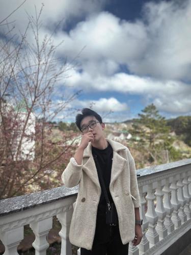 a man wearing glasses and a coat standing on a balcony at Lưng Chừng House in Da Lat