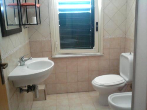 ジャルディーニ・ナクソスにあるAppartamento Glass Cinquecentoのバスルーム(洗面台、トイレ付)、窓が備わります。