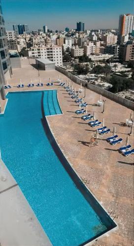 a swimming pool with chairs and umbrellas on a beach at Luxury Apartments - Ajman Corniche UAE in Ajman