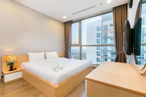 a bedroom with a bed and a desk and a tv at Jessie Saigon Apartment - Vinhome Central Park in Ho Chi Minh City