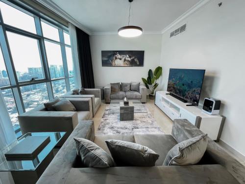 a living room with a couch and a tv at CMA Skyline Sanctuary Apartments - Ajman Corniche UAE in Ajman 