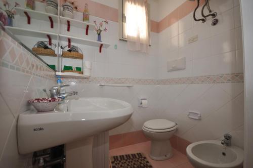 a white bathroom with a sink and a toilet at Villa Ridente Maria in Gioiosa Marea