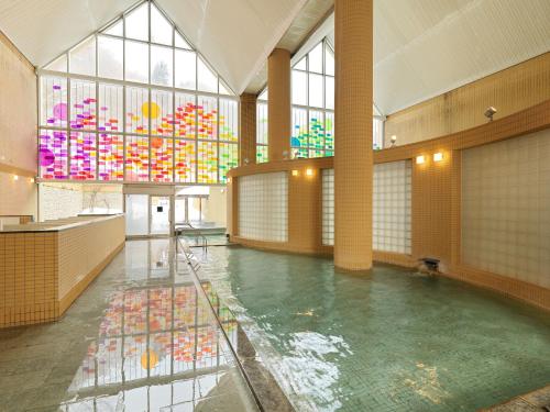 Jozankei Tsuruga Resort Spa Mori no Uta في Jozankei: تجمع كبير للمياه في مبنى به نوافذ