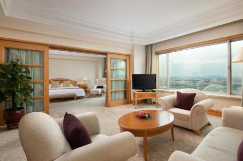 una sala de estar con una habitación con cama y TV en Grand Metropark Hotel Nanjing, en Nanjing