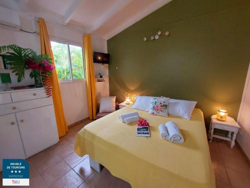 Un dormitorio con una cama amarilla con toallas. en Gîtes Les Bienheureux - Piscine, Hamak, Terrasse, en Anse-Bertrand