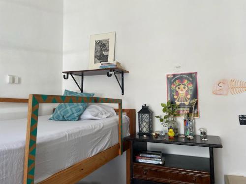 a bedroom with a bed and a table with a night stand at La Casa del Kéej Hostel in Mérida