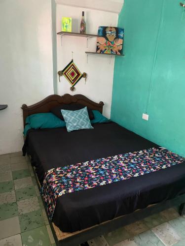 a bed in a room with a blue wall at La Casa del Kéej Hostel in Mérida