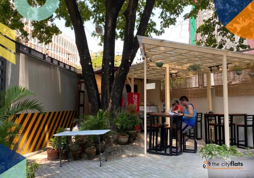 two people sitting at a table under a pergola at The City Flats Amorsolo in Manila