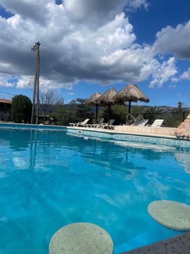a swimming pool with chairs and umbrellas at MIRADOR DE ESTRELLAS RESORT in Nono
