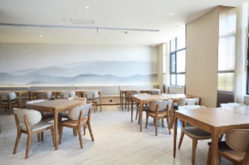 - une salle à manger avec des tables, des chaises et des fenêtres dans l'établissement Ji Hotel Zhangye West Station, à Zhangye