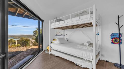 ein Schlafzimmer mit einem Etagenbett und einem großen Fenster in der Unterkunft Merimbula Heights 2 in Merimbula