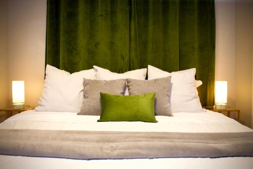 uma cama com almofadas brancas e uma cabeceira verde em Cozy 2 King 2 Twin Cottage em Hattiesburg