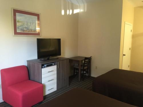 a room with a tv and a chair and a desk at Beachview Inn in Santa Cruz